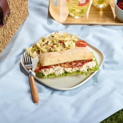 Caesar Sandwich with Ferme des Voltigeurs Grain-Fed Chicken Spread, served with a pasta salad in a picnic setting.