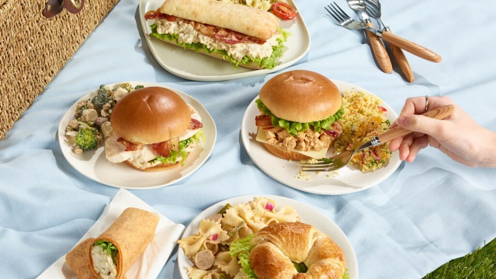 Variété de sandwichs et salades Ferme des Voltigeurs, ambiance pic-nic. / A Variety of Sandwiches and Salads in a Picnic-Style Setting.