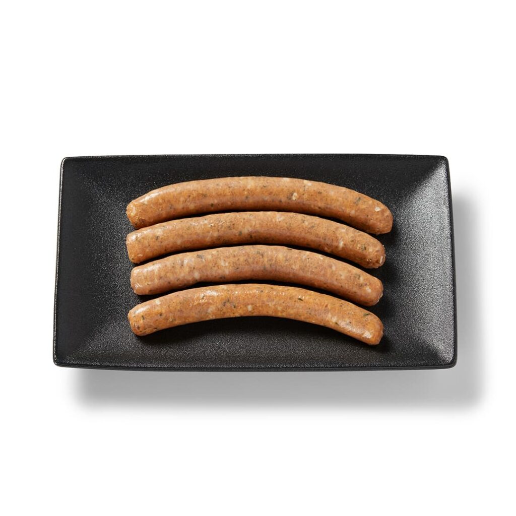 Saucisse de poulet aux fines herbes Ferme des Voltigeurs sur un plateau de présentation