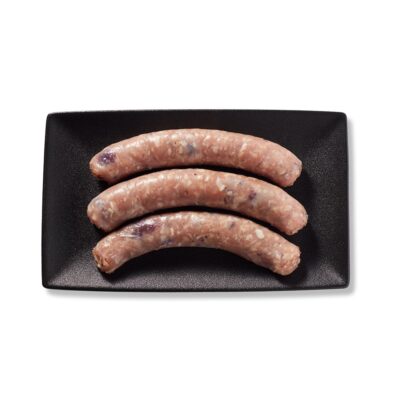 3 saucisses pommes et canneberges de Ferme des Voltigeurs dans une assiette noire sur fond blanc. / Three Ferme des Voltigeurs Apple & Cranberry Sausages on a Black Plate with a White Background.