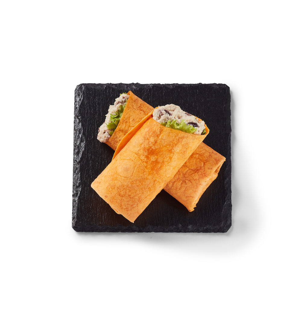 Wrap tartinade poulet et canneberges Ferme des Voltigeurs, assiette noire sur fond blanc. / Ferme des Voltigeurs Chicken and Cranberry Spread Wrap on a Black Plate with a White Background.